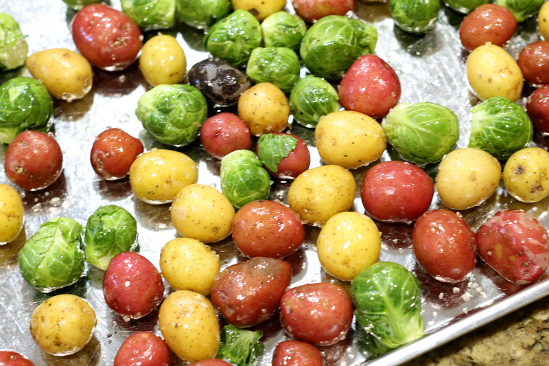 Brussel sprout and baby potatoes on a baking sheet.