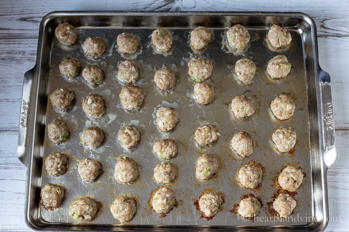 Meatballs on a baking sheet after cooking in a oven.