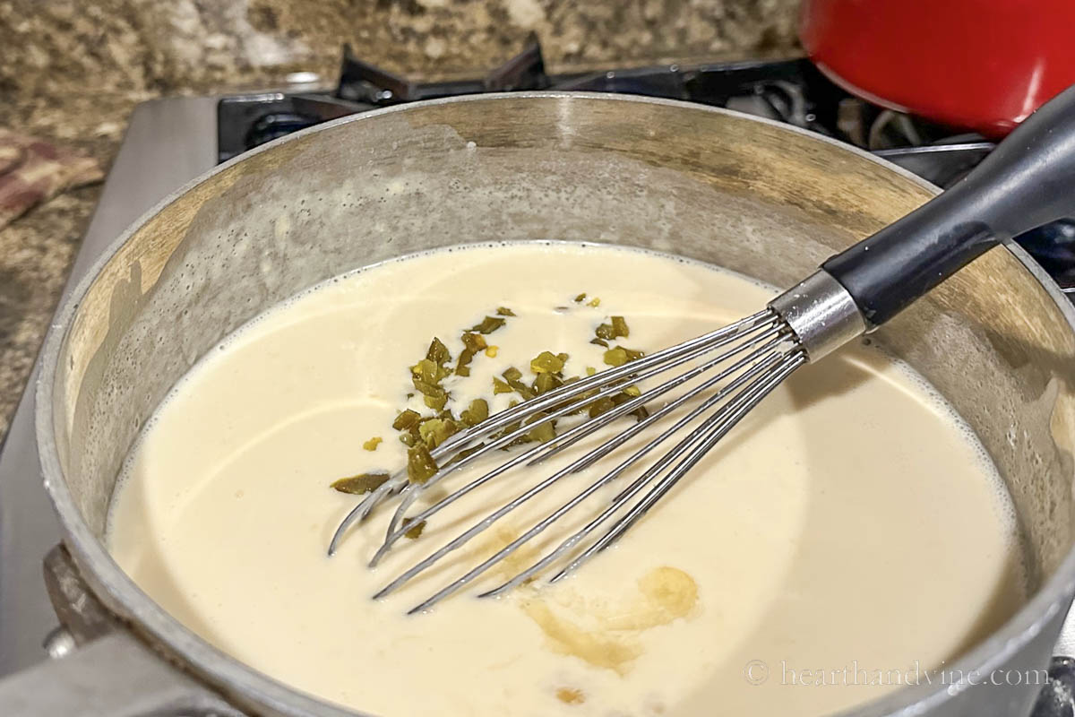 Adding chopped marinated jalapenos and juice to the cheese mixture.