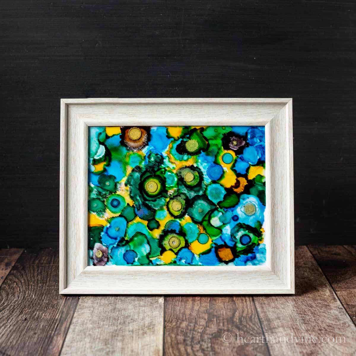 Alcohol ink in glass painting in a frame on a table.