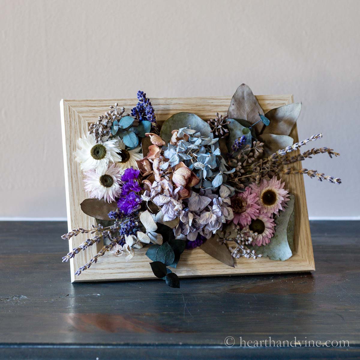 Dried flower art in a frame set on a table.