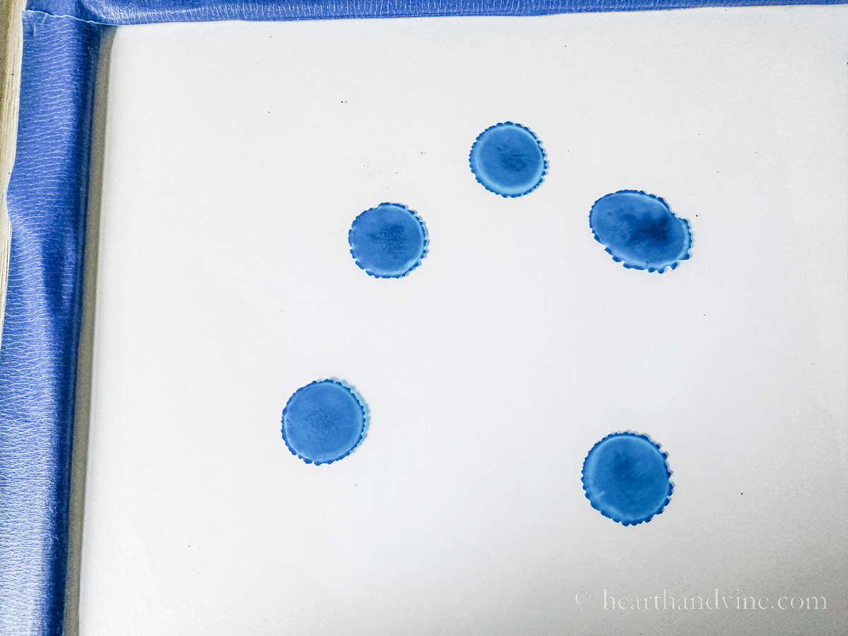 Spreading drops of blue alcohol ink on glass photo frame.