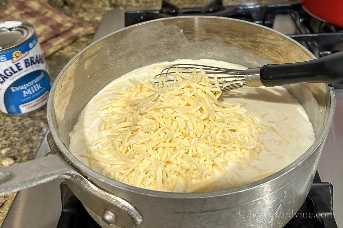 Adding shredded cheese to the evaporated milk.
