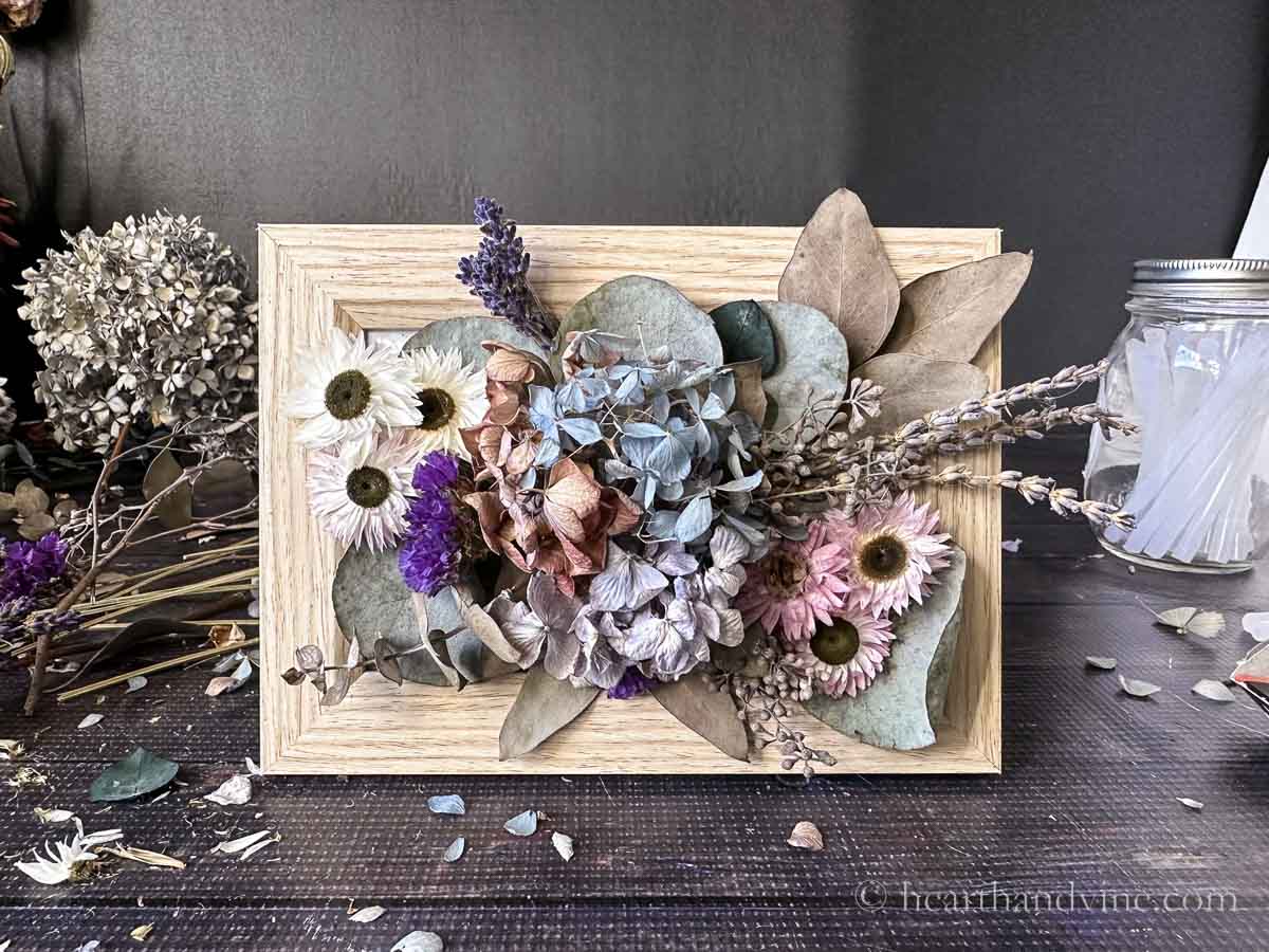 Dried flowers arranged and glued to a light wood picture frame glass.