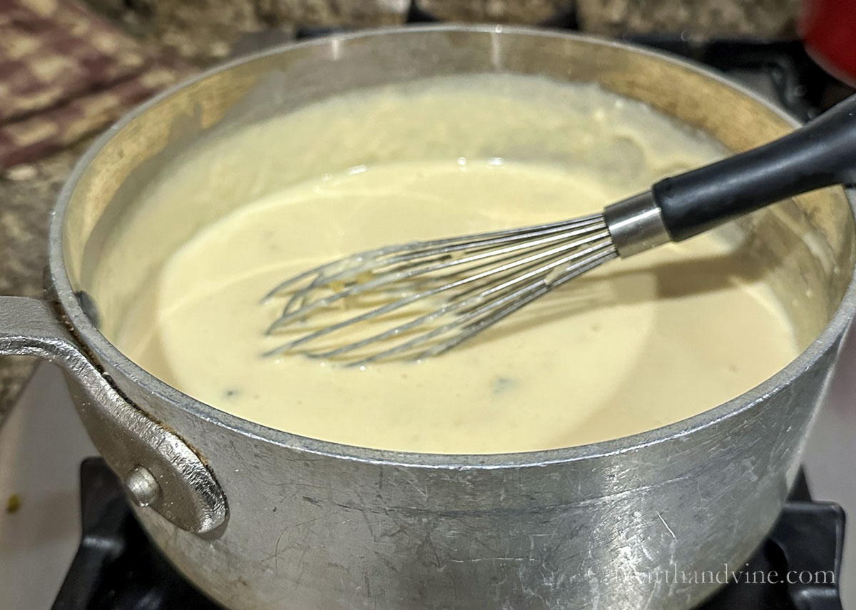 Queso dip with a whisk on the stove.