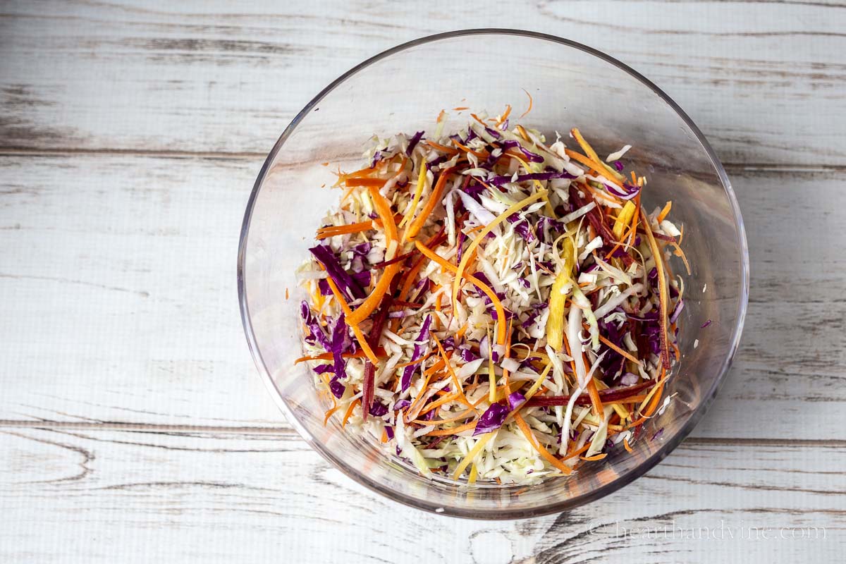 A large clear bowl filled with shredded and julienne vegetables.