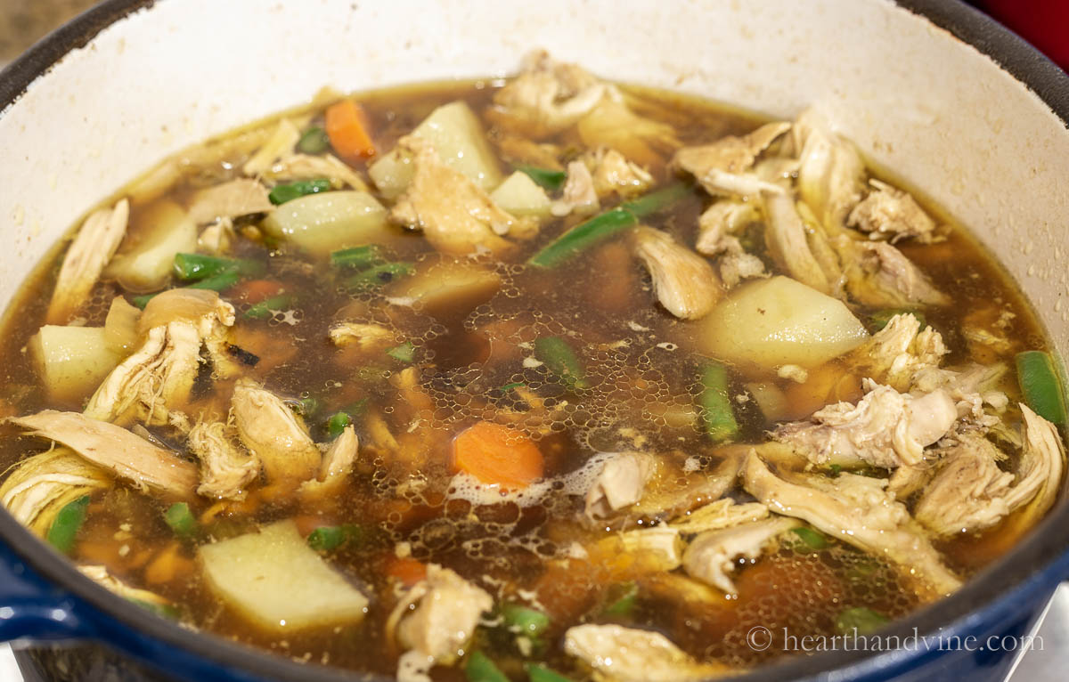 Chicken stew simmering in a pot on the stove.
