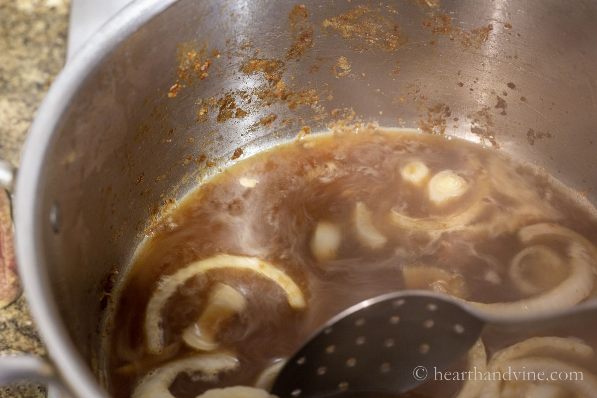 Scraping the pot to deglaze and remove bits of beef from the bottom of the pan.