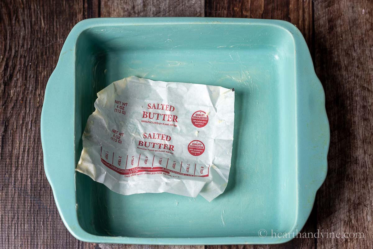 Greasing a baking dish with residual butter on butter paper.