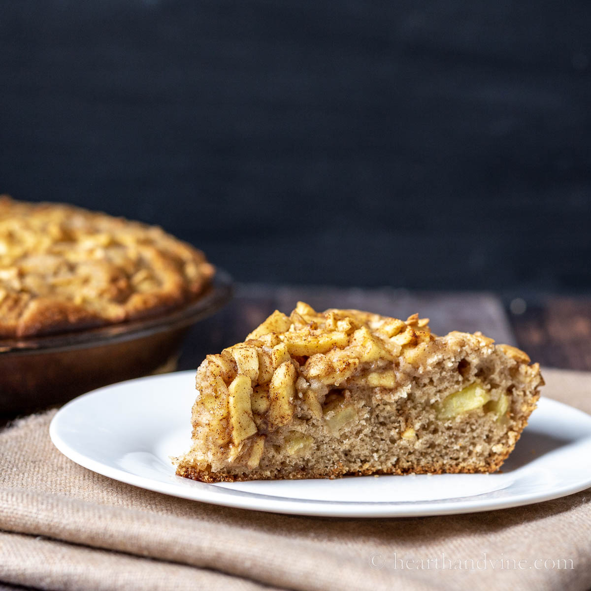 Slice of apple cake next to the baking pan.