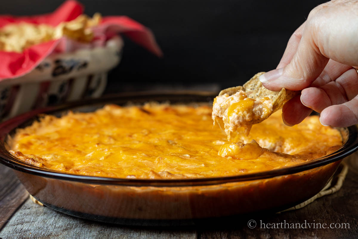 A hand scooping out some of the buffalo chicken dip with a scoop chip.