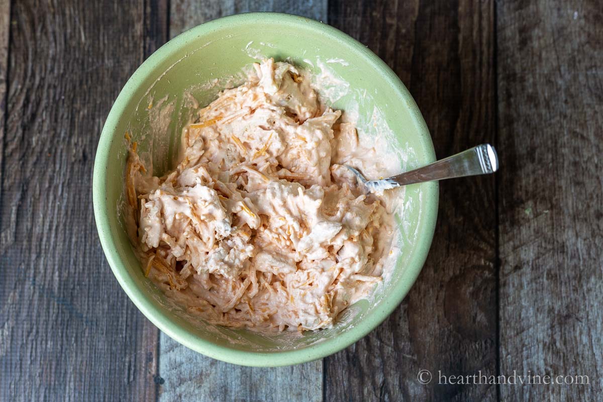 Ingredients for buffalo chicken dip without cream cheese mixed together in a mixing bowl.