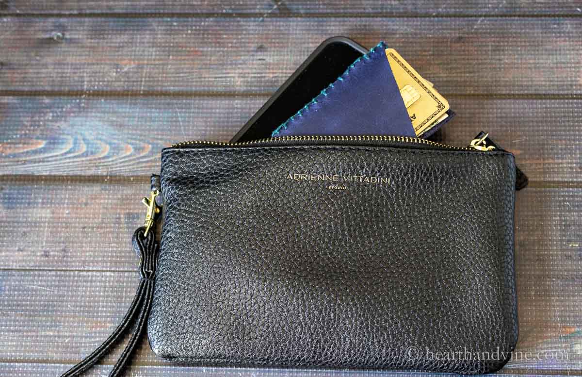 A black evening clutch with a phone and a credit card holder peeking out the top.
