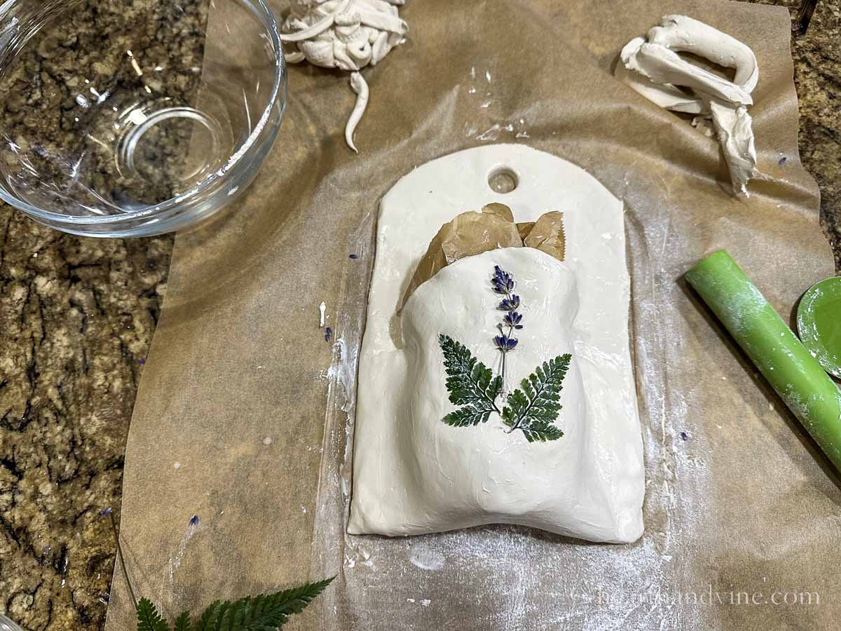 Lavender flowers and ferns pressed into the top of the clay wall pocket.
