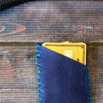 Small leather hand stitched card holder in blue with credit cards inside.