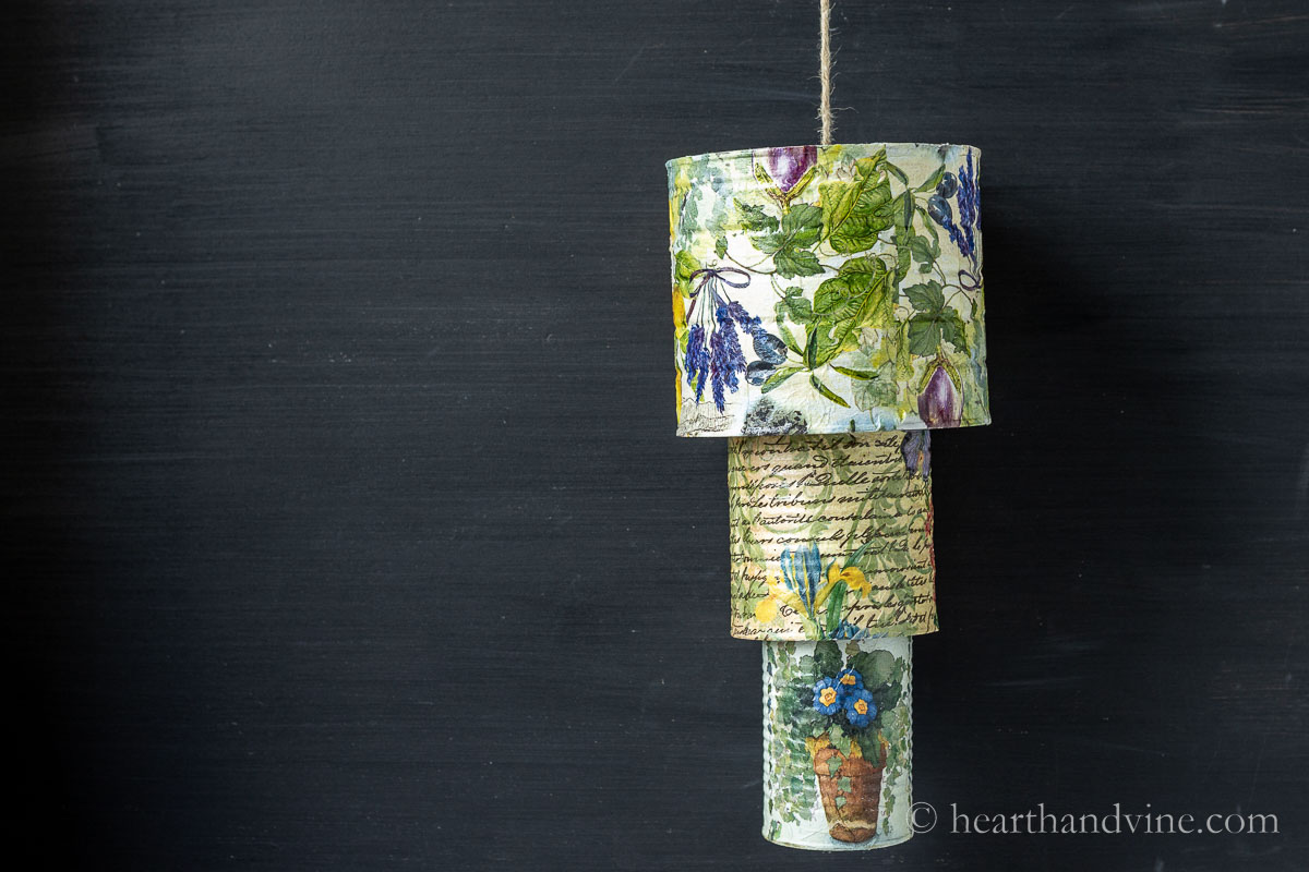 Tin can wind chimes complete and hanging in front of a chalkboard.