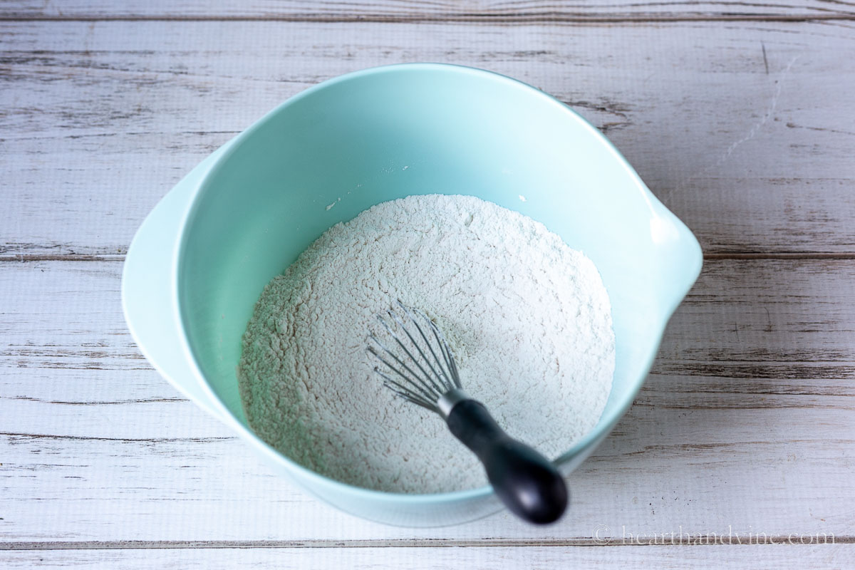 Dry cookie ingredients of flour, salt and baking soda in a mixing bowl with a wire whisk.
