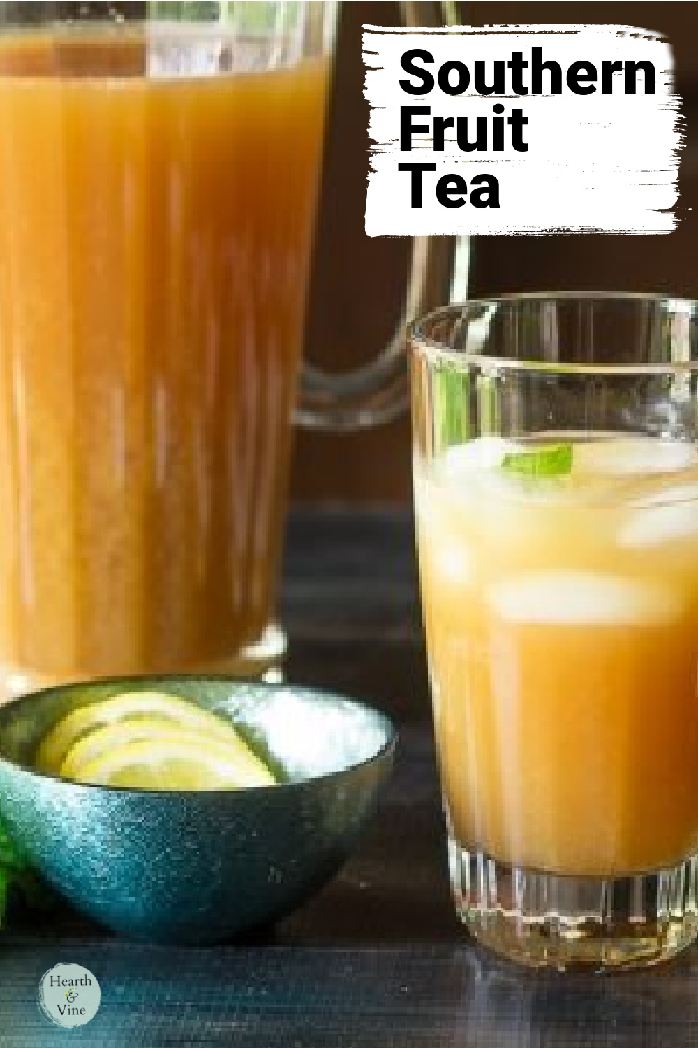 Pitcher and glass of fruit next to a small bowl of sliced lemons.