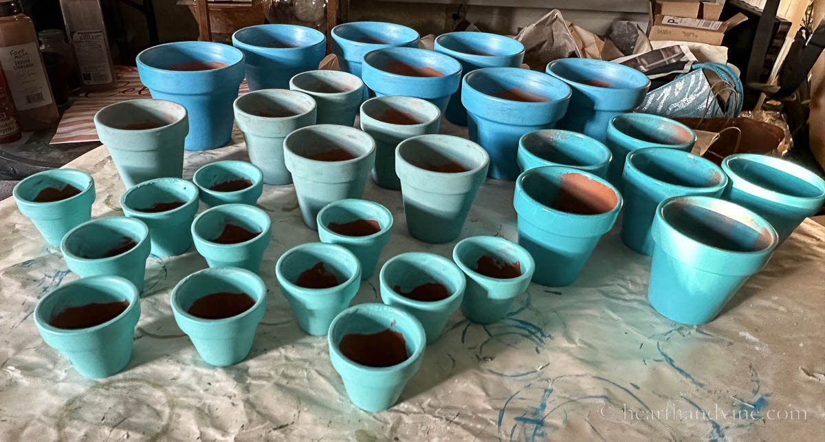 Various sized clay pots painted in shades of blue.