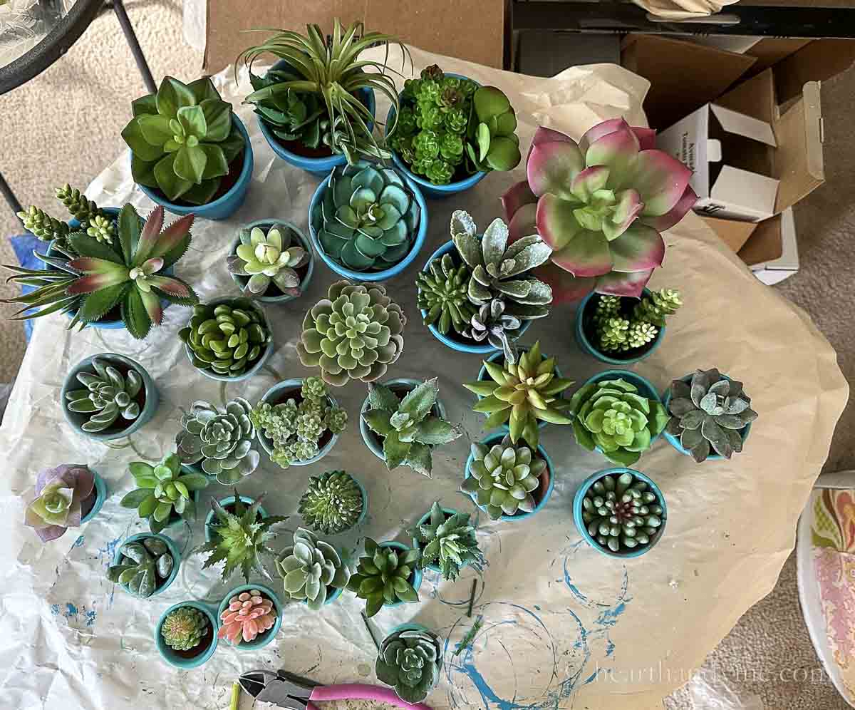 Various sized small clay pots with faux succulents inside each pot.