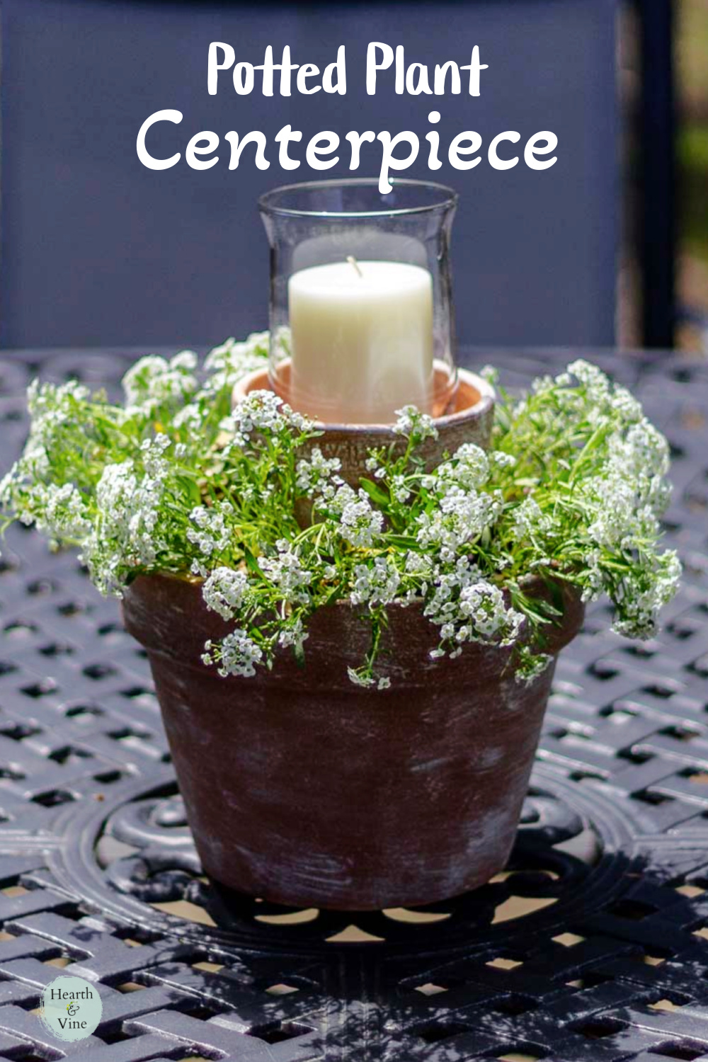Nested clay pots with a candle and small white flowers.