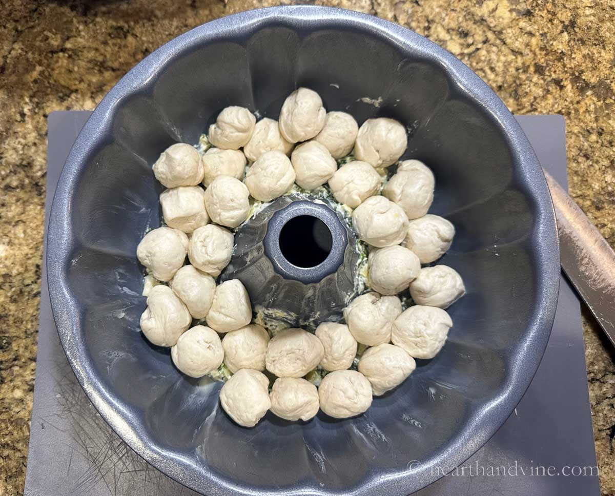 Ball of biscuit dough on top of the spinach mixture in the bundt pan.