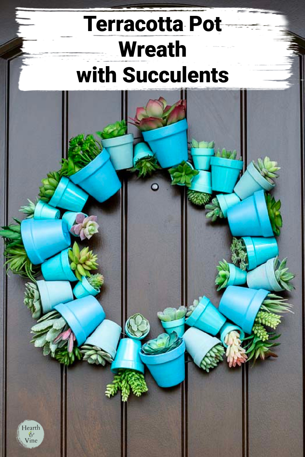 Clay pot wreath in shades of blue with faux succulents inside hanging on a door.