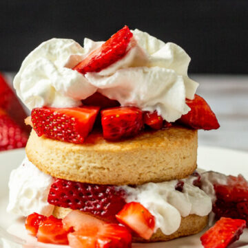 Stacked strawberry shortcakes with fresh strawberries and whipped cream.