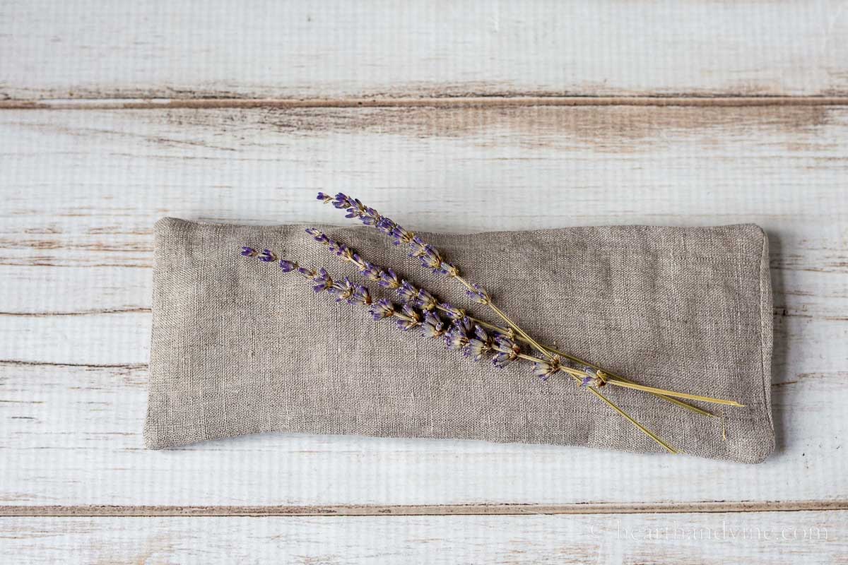 A linen eye pillow with a few stems of dried lavender.