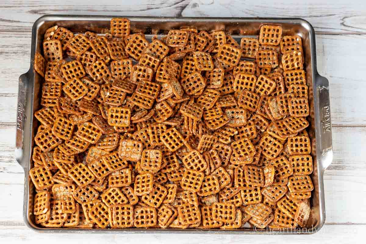 Baking sheet with square pretzels covering in a seasoned oil mixture.