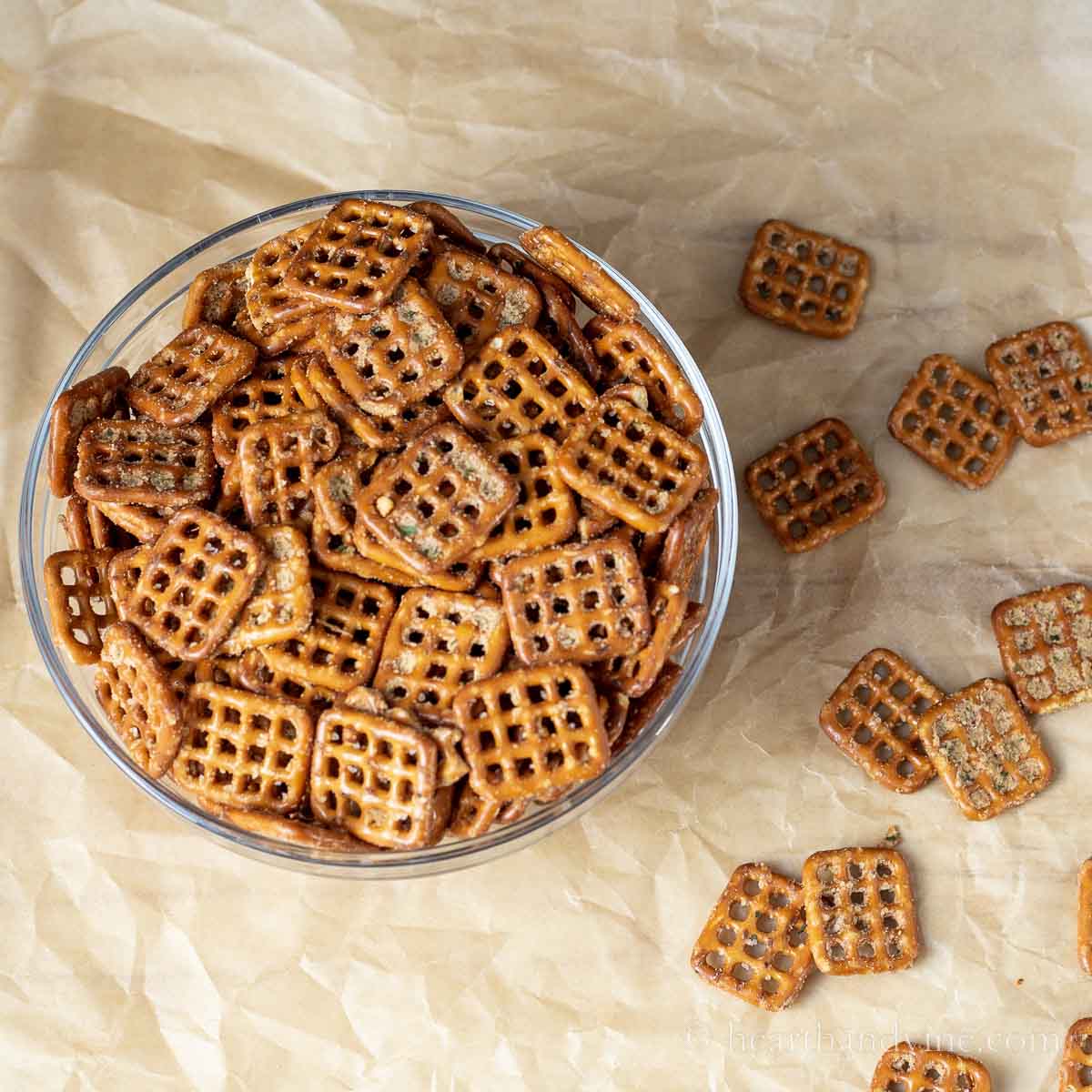 Bowl of spicy seasoned pretzels with a few scattered around the table.