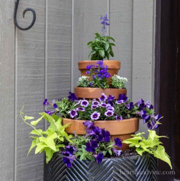 Stacked clay pots on a planter to create height filled with colorful annuals.