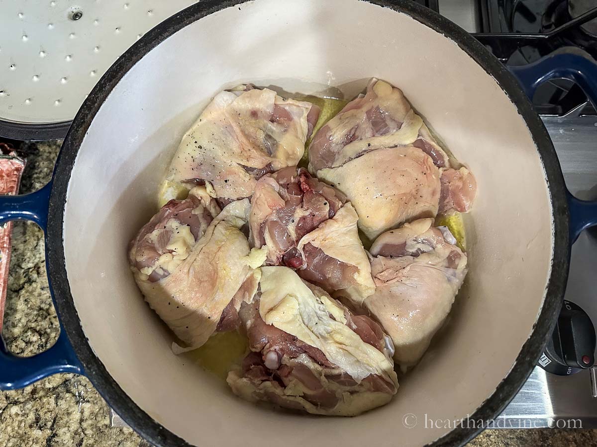 Chicken thighs browning in a Dutch oven.