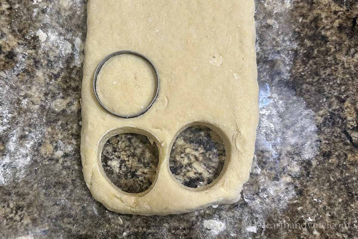 Cutting out round scones with a biscuit cutter.