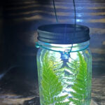 Lighted mason jar lantern with ferns.