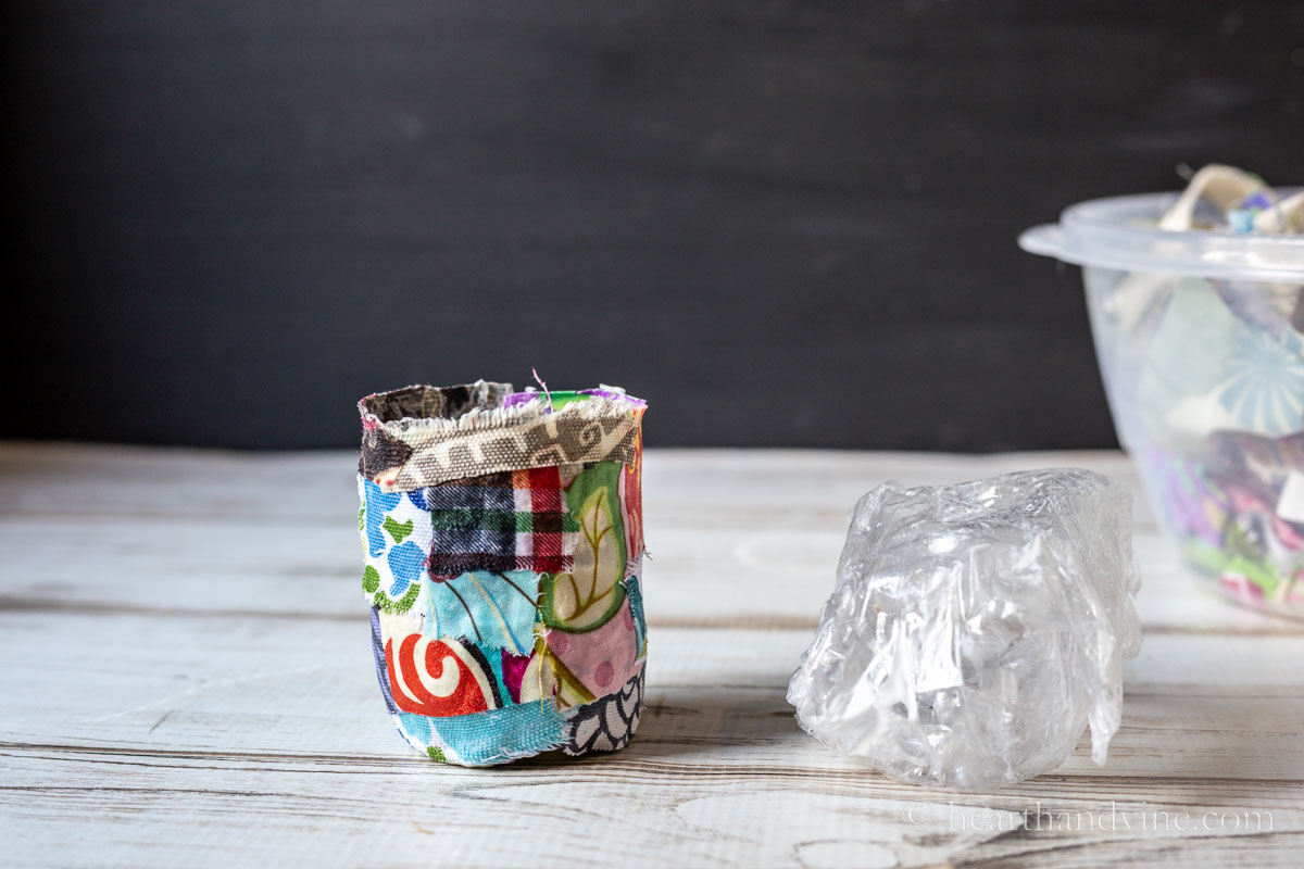 Finished fabric pot next to the plastic wrap covered cut bottom portion of a water bottle.