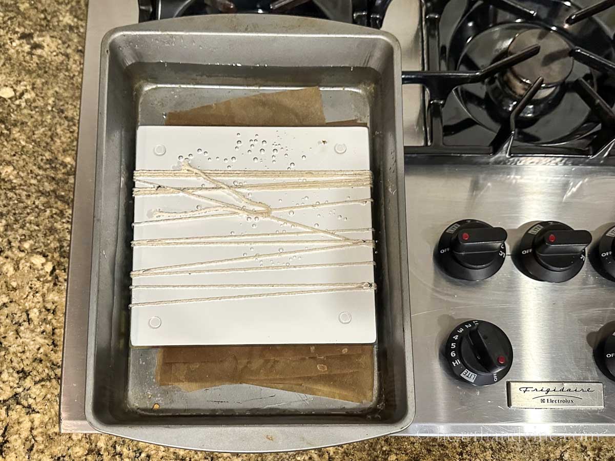 Eco printing paper bundle in a roasting pan of water simmering on the stove.