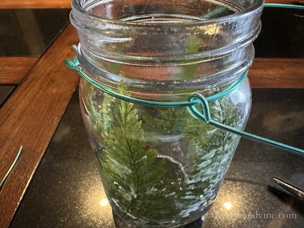 A wire loop adds a handle to a wire base on the neck of a mason jar.