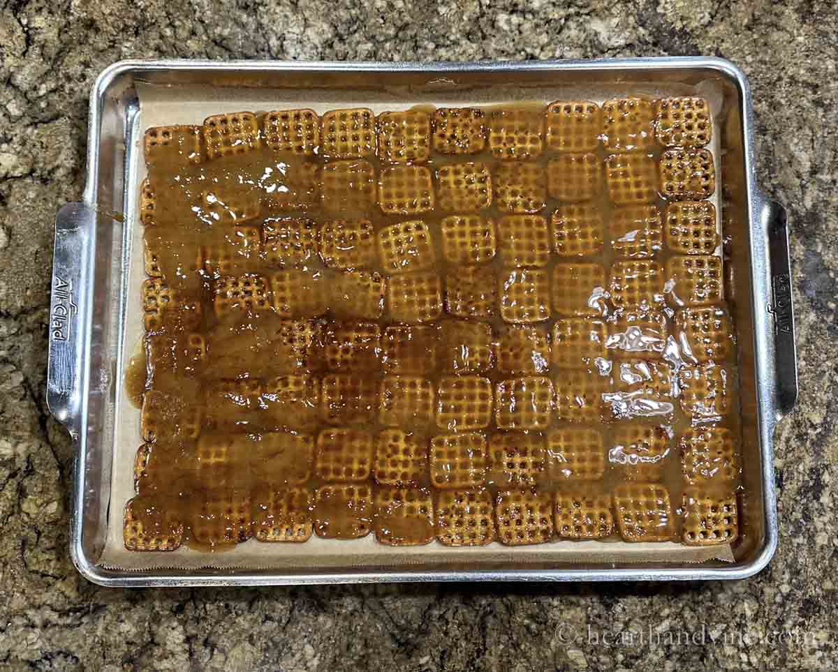 Pretzels lining a jelly roll pan with caramel liquid spread on top.