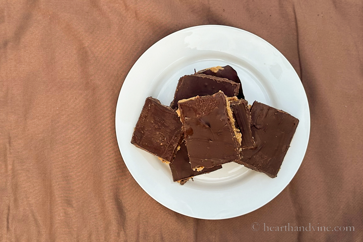 Chocolate peanut butter bars cut up and stacked on white plate.