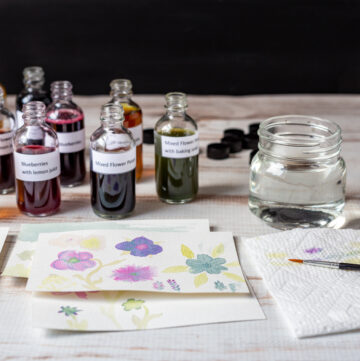 Watercolor inks in bottles and a few small painting on the table.