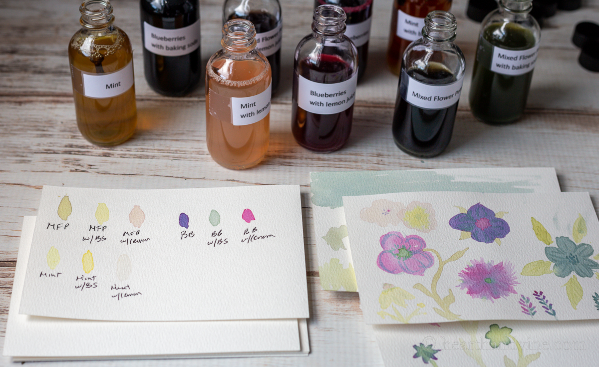 Labeled bottles of homemade watercolors and a jar of water, a test paper, and a couple of flower paintings. 