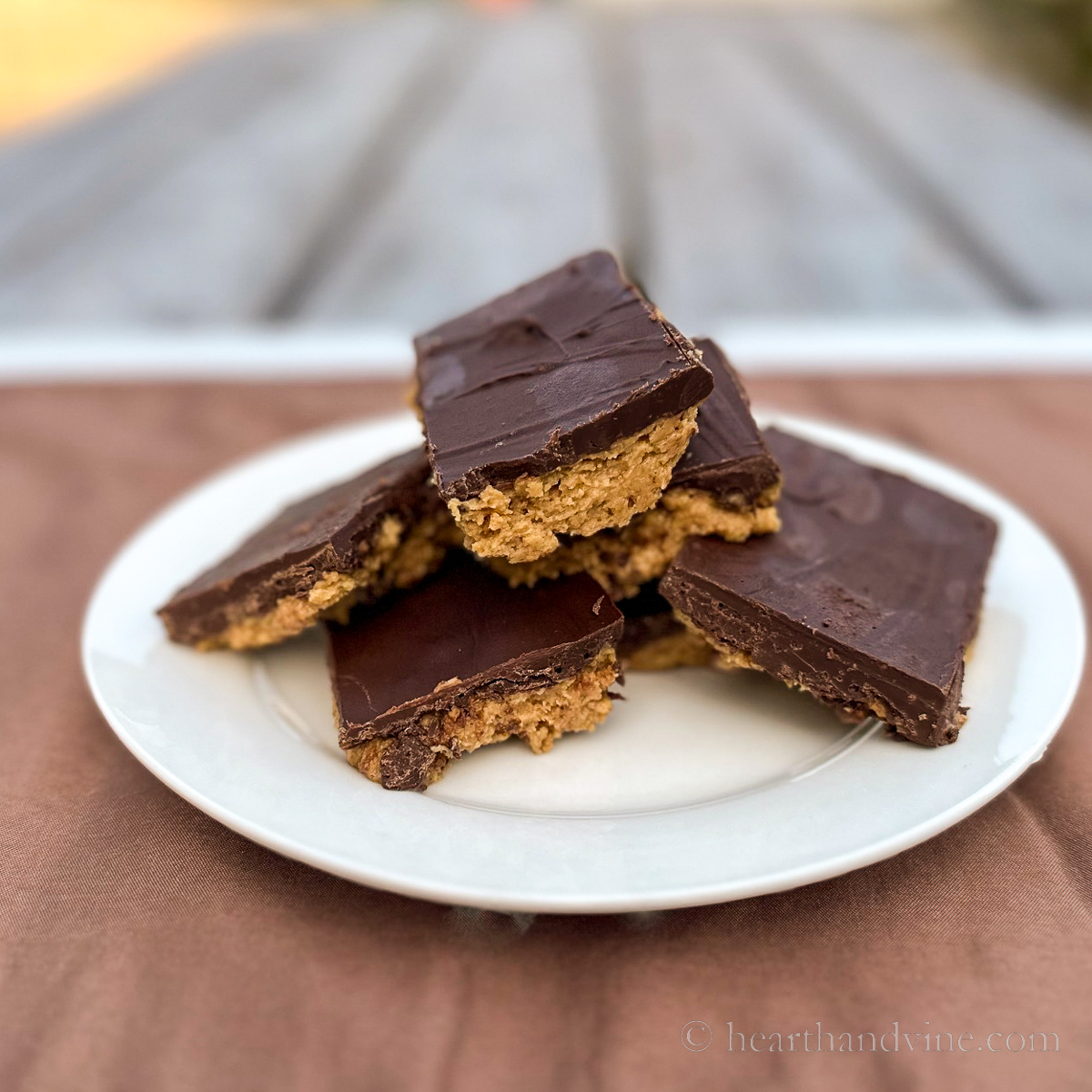 Stacked chocolate peanut butter bars on a plate.