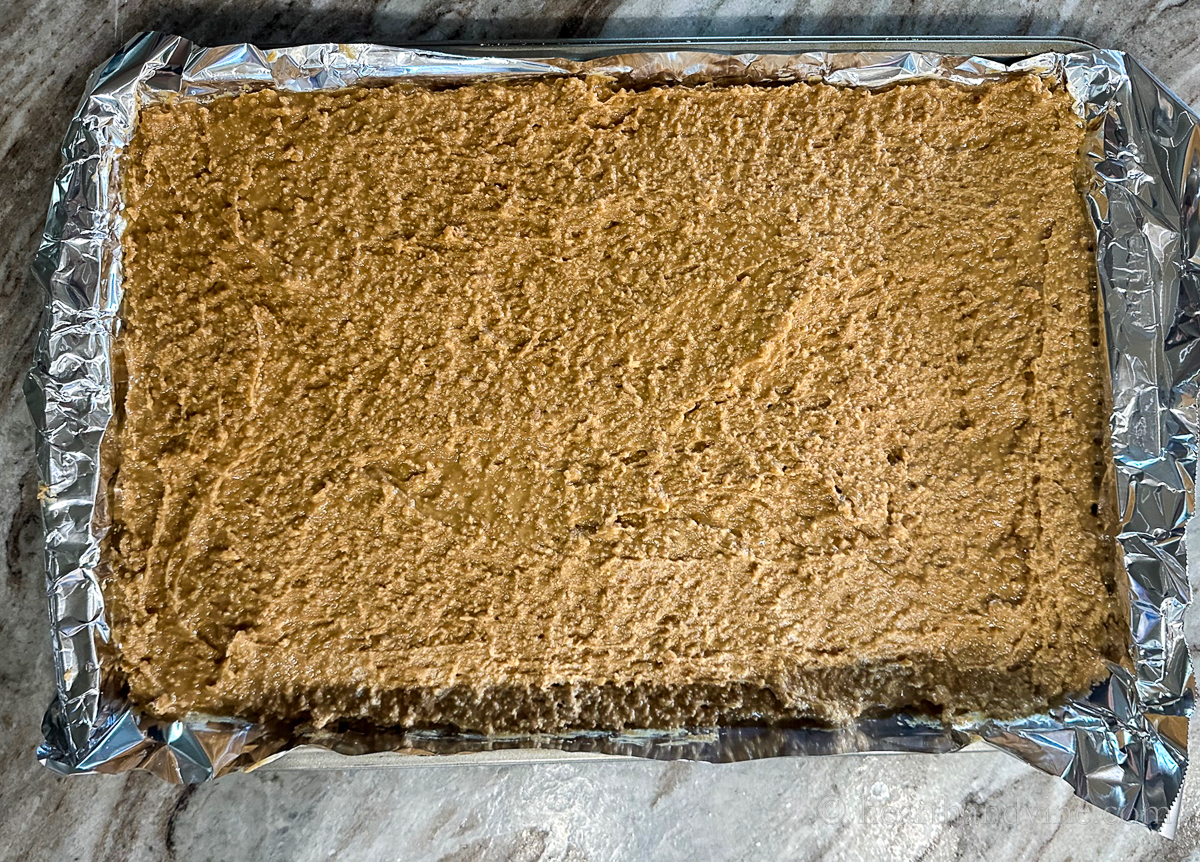Peanut butter mixture spread into a foil lined baking pan.