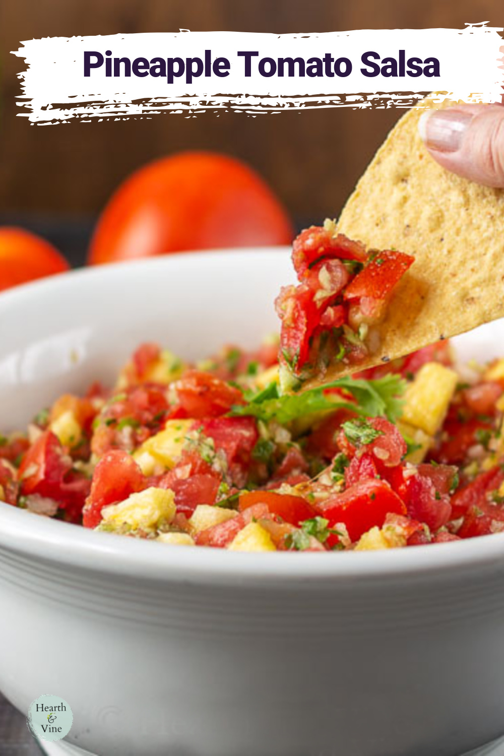 Tortilla chip lifting some pineapple salsa from a bowl.