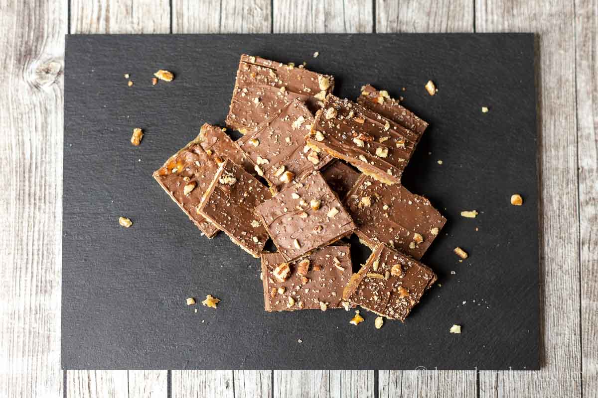 Pretzel toffee cut up in pieces on a black slate serving tray.