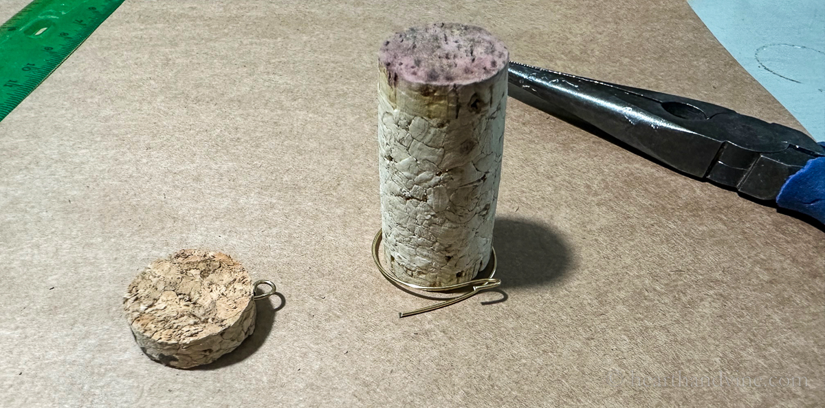 Gold wire wrapped around a wine cork and a slice of cork with a small gold wire loop.