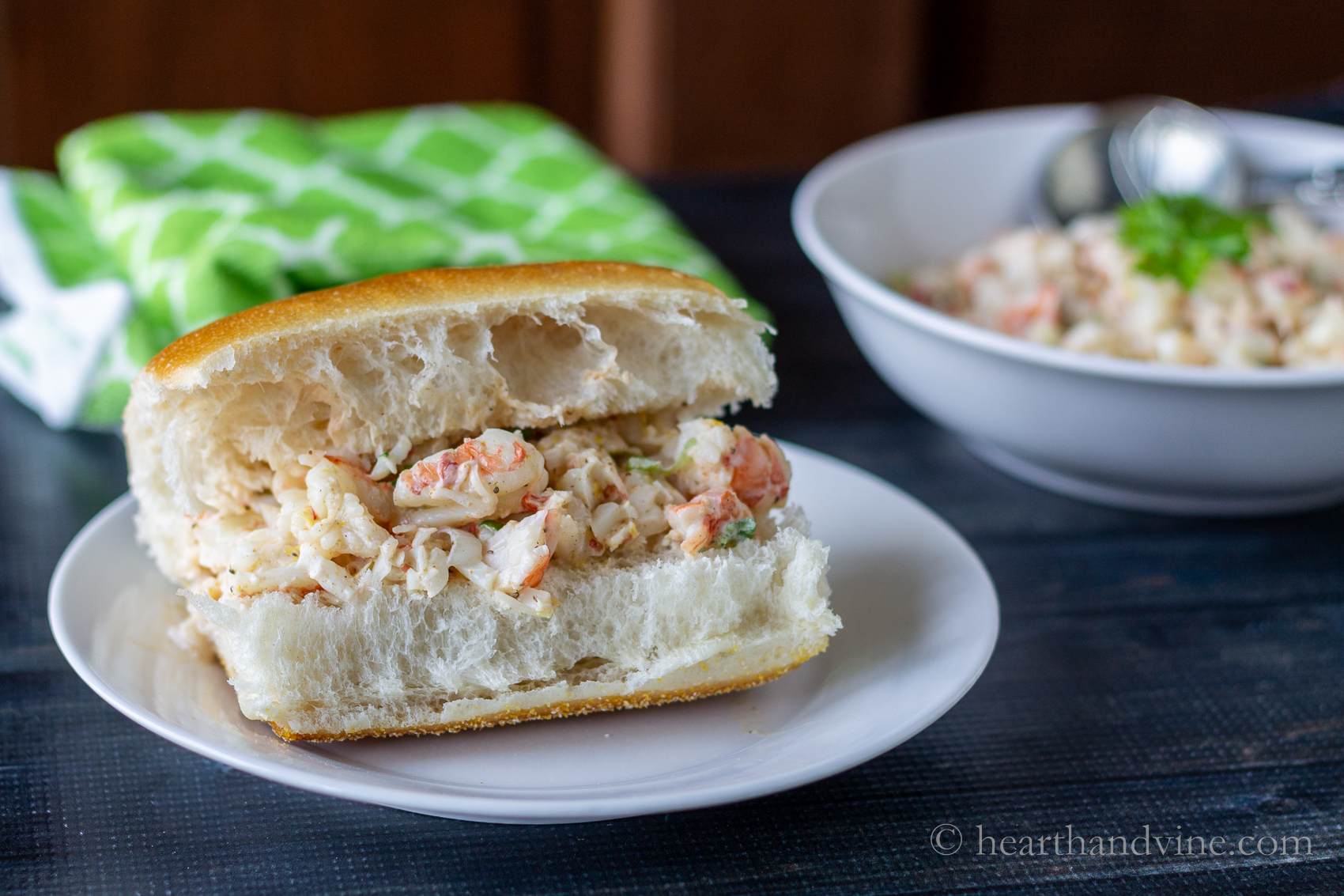 Shrimp salad on a hoagie roll next to a bowl of the same salad.