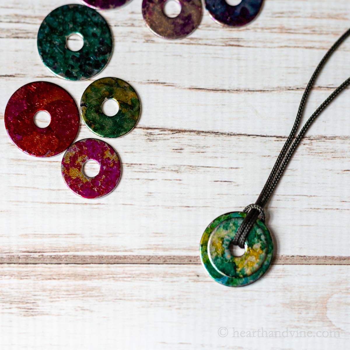 Alcohol in washer necklace next to a few decorated washers with alcohol inks.