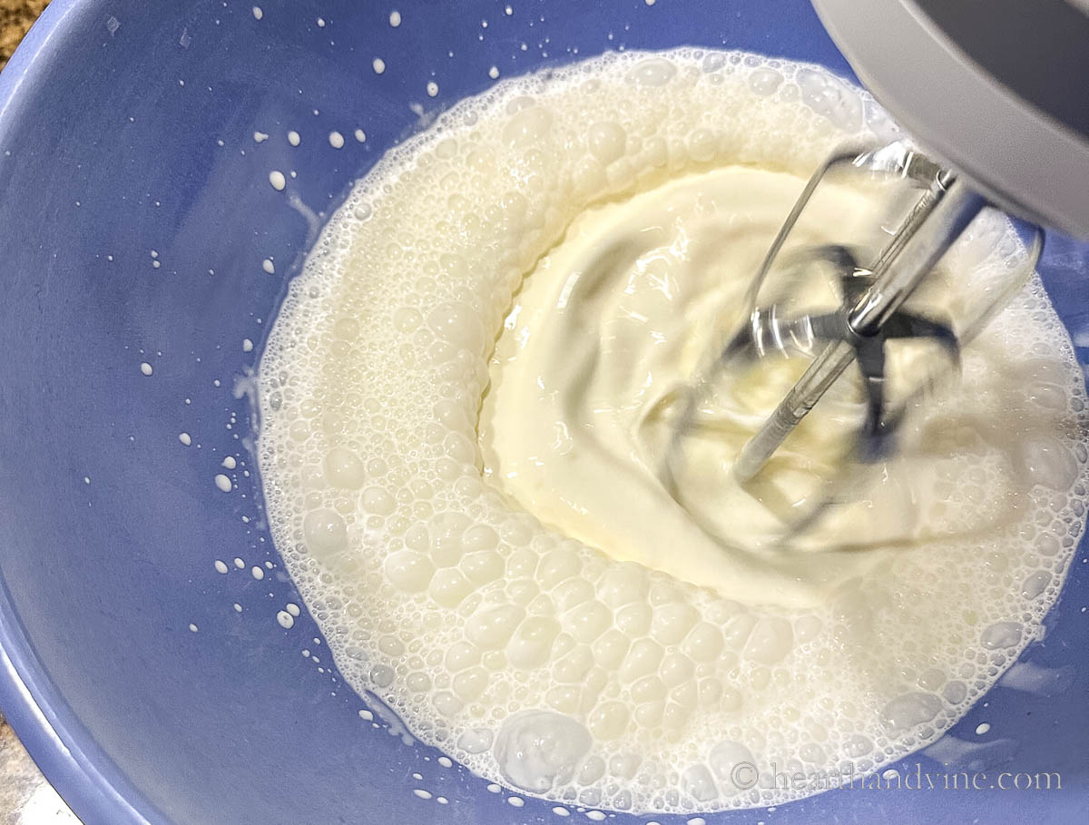 A hand mixer beating heavy whipping cream.